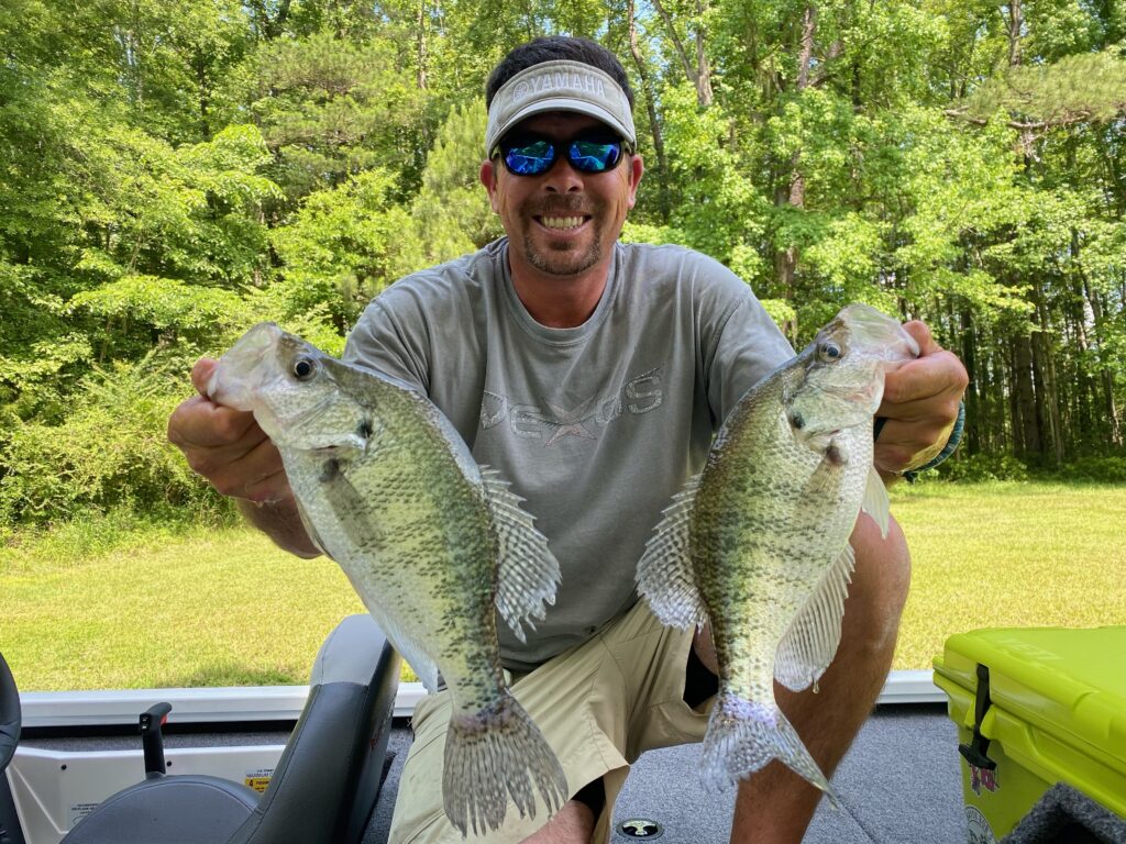 Captain Jason Domangue holding two crappie on his boat